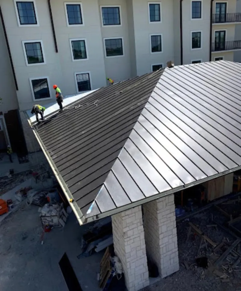 Crew installing standing seam metal roof panels on a commercial project in Oxford